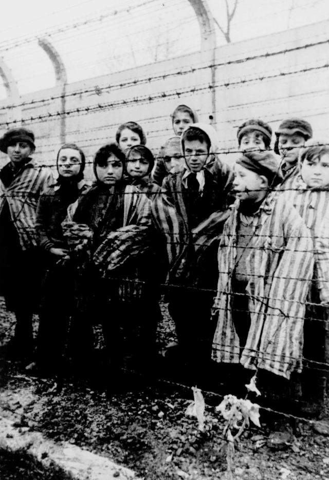 Eine Gruppe gefangener Kinder in Haeftlingskleidung blickt durch einen Zaun aus Stacheldraht im Konzentrationslager Auschwitz, kurz nach der Befreiung des Lagers durch sowjetische Truppen Ende Januar 1945. Die Befreiung jaehrt sich am Dienstag, 27. Jan. 2004, zum 59. Mal. Dieser Tag ist seit 1996 in Deutschland der zentrale Gedenktag fuer die Opfer des Nationalsozialismus. (KEYSTONE/AP Photo/Holocaust Museum)